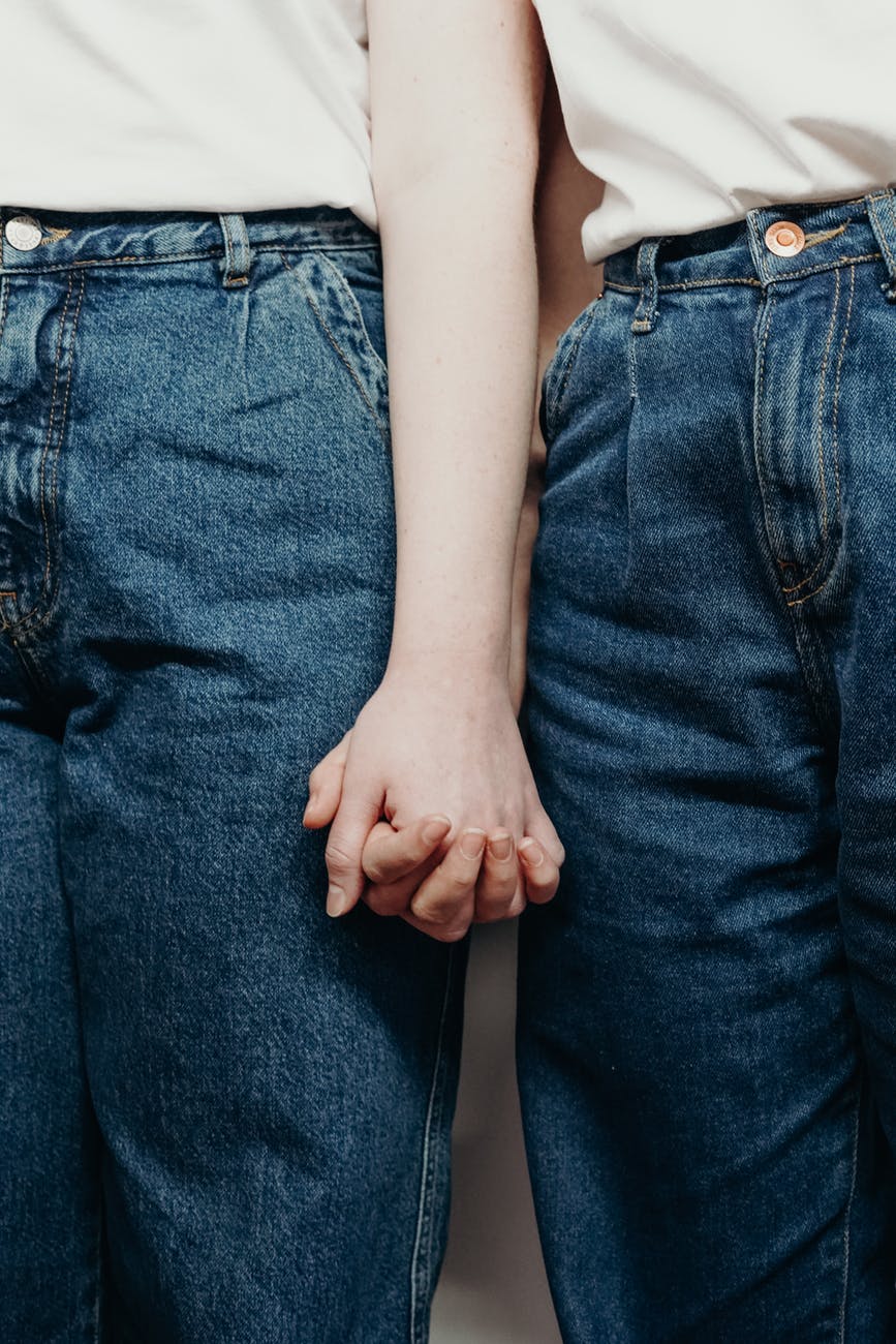 persons wearing denim jeans while holding hands